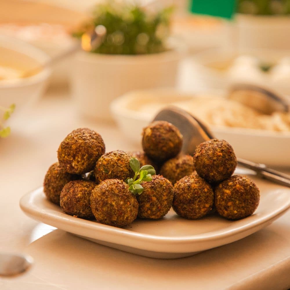 Assiette de falafel croustillants dressée devant des bols de houmous