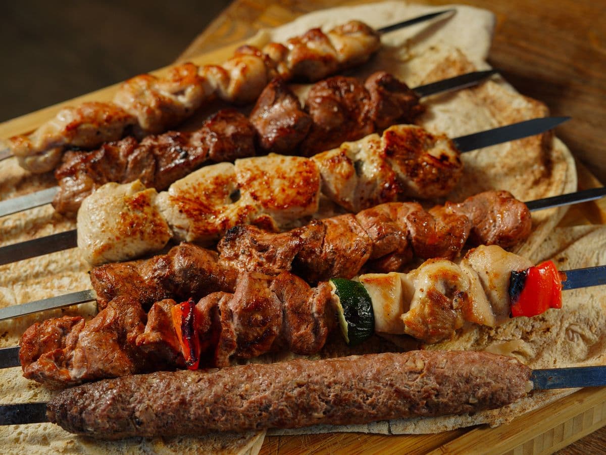 Brochettes grillées d'agneau, de poulet et de kefta posées sur du pain libanais