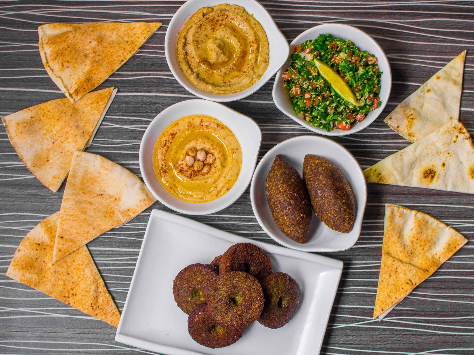 Plateau de mezzé libanais : houmous, moutabal, taboulé, kibbeh et falafel servis avec du pain pita