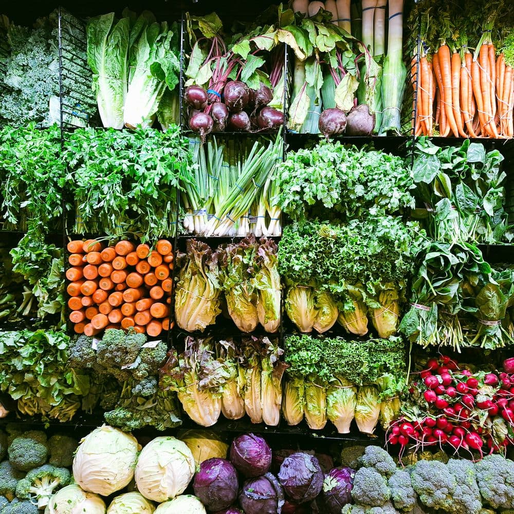 Étal de marché garni de persil, salades, carottes, radis et légumes de saison
